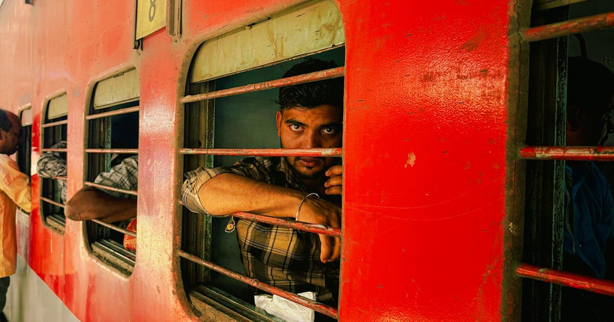 Man looking out from Indian railway train window during his journey