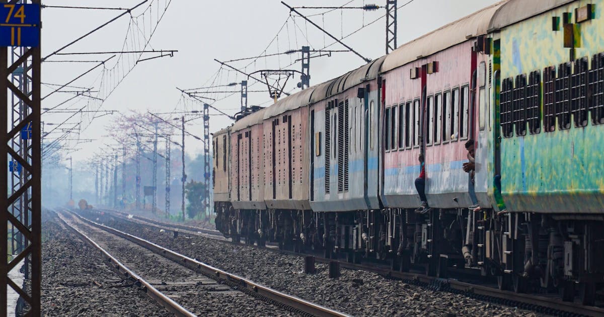 Passenger train running on Indian railway track under electric wires